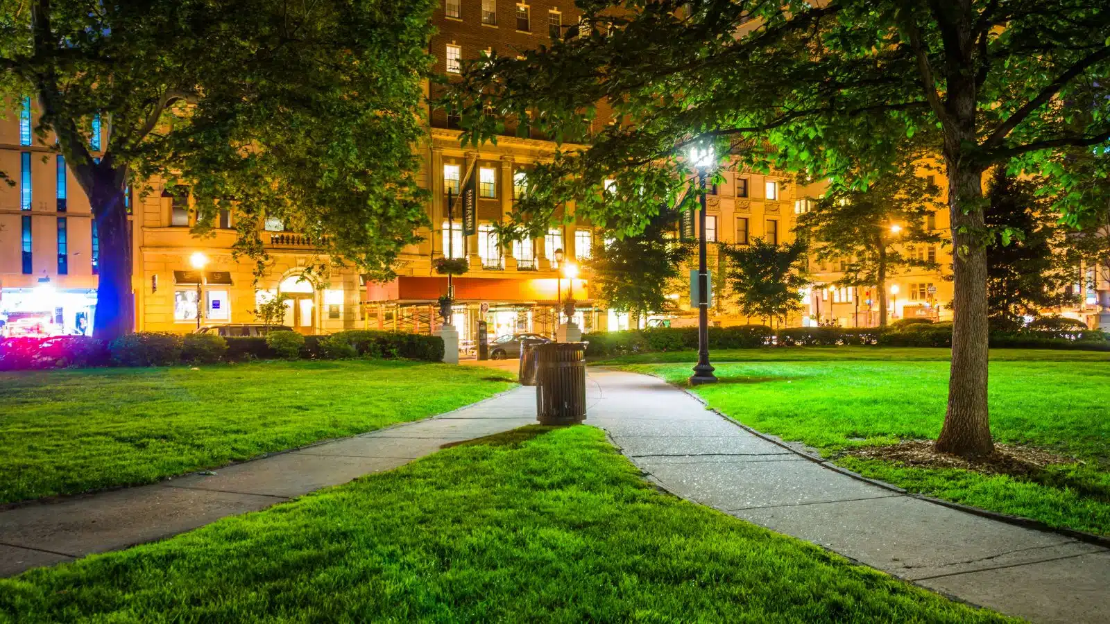 The lush grass and paths at Rittenhouse Square in Philadelphia lit up in the evening.