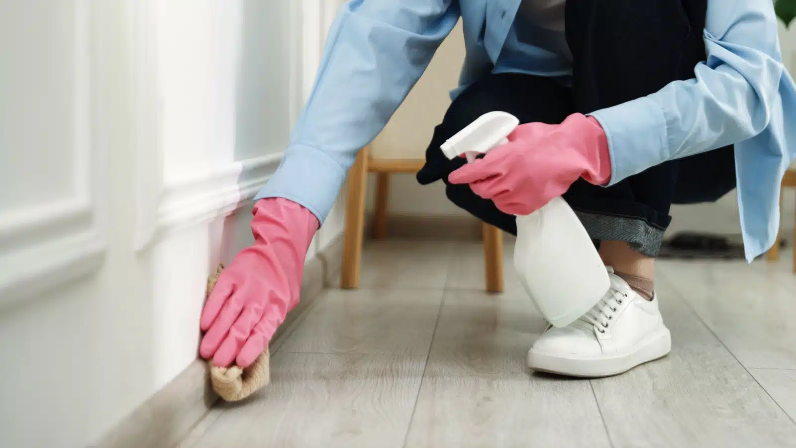 Close up of a woman cleaning baseboards.