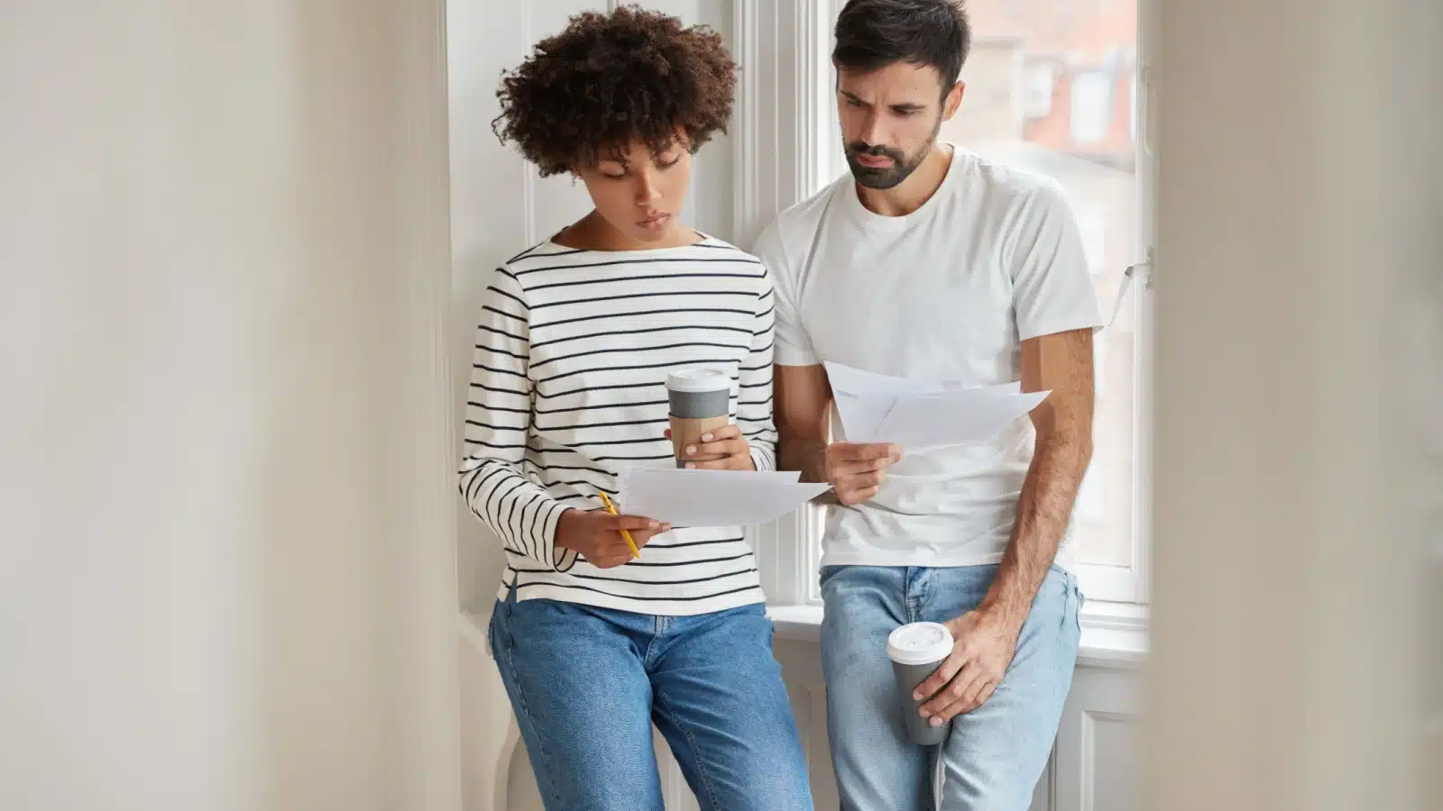 A worried couple looks at their bills and budget, unsure how to pay everything.