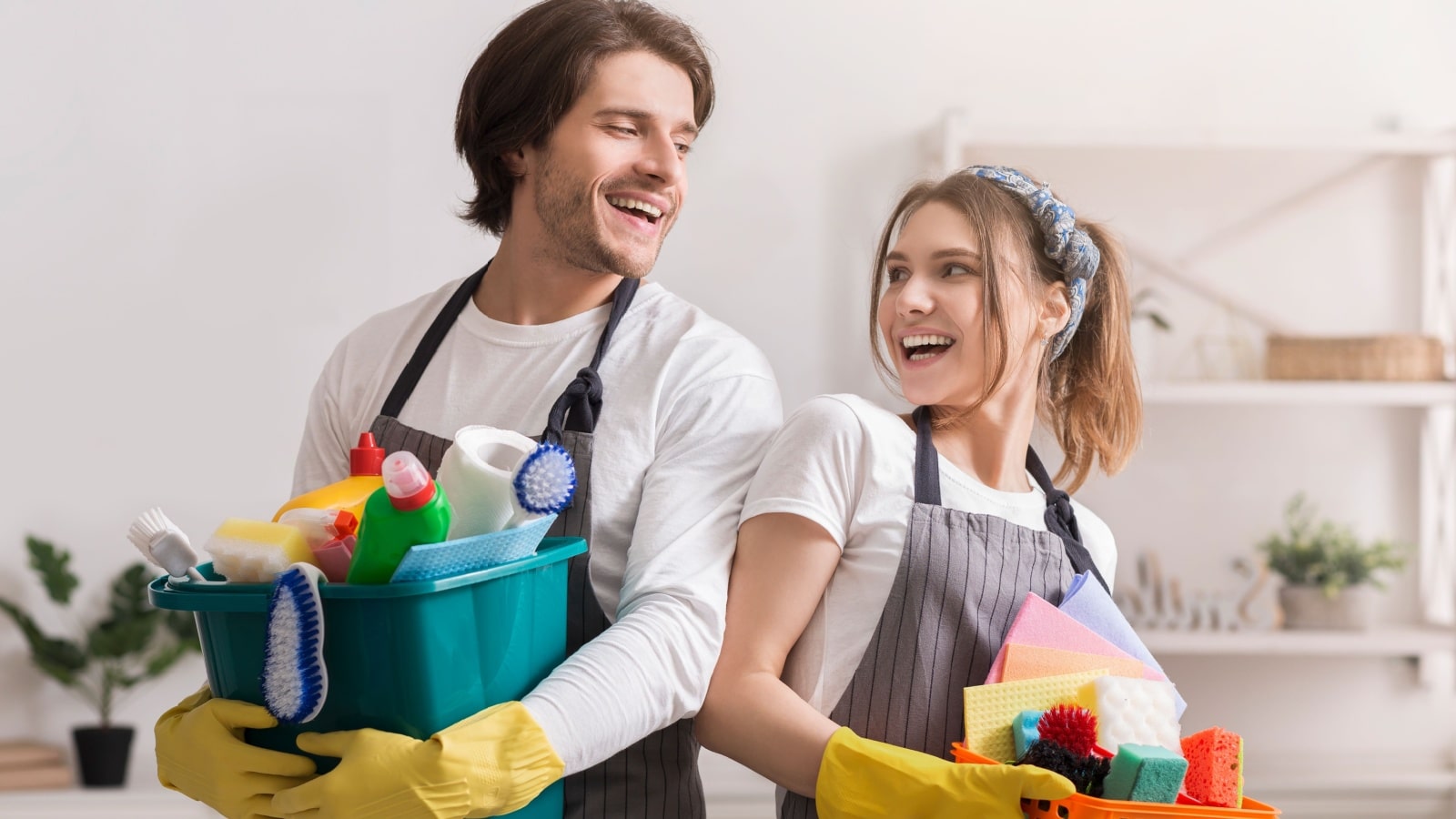 A happy couple holds cleaning supplies, getting ready for spring cleaning.