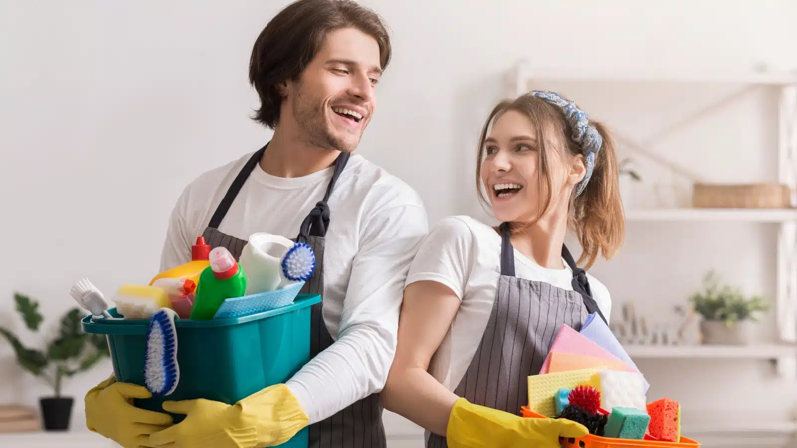 A happy couple holds cleaning supplies, getting ready for spring cleaning.