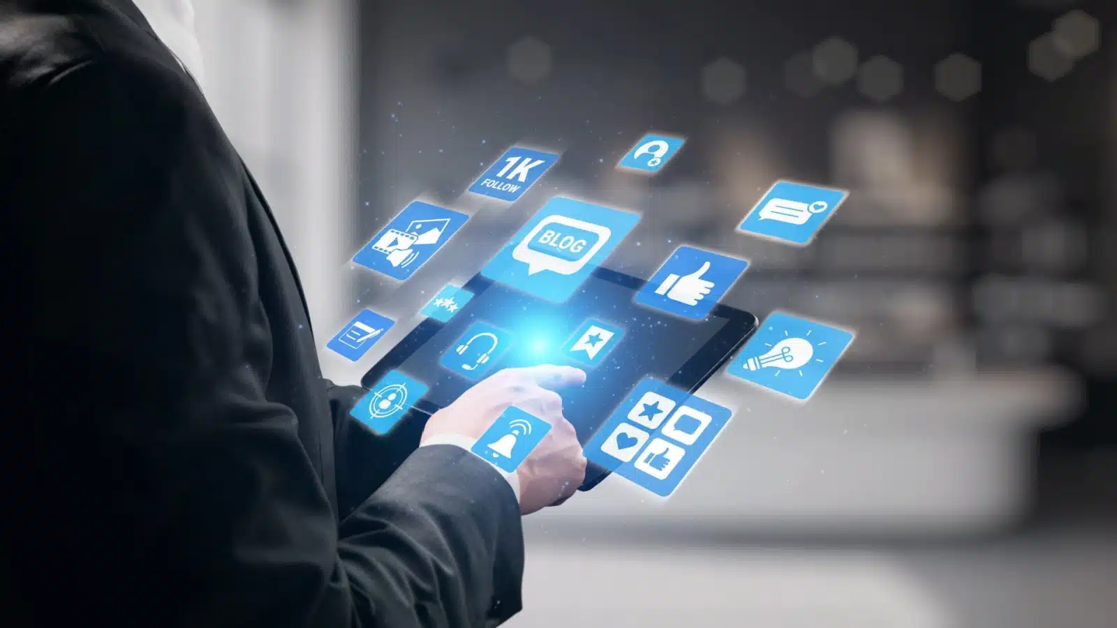 A person holds a tablet projecting various icons for blogging, social media, and general content creation.