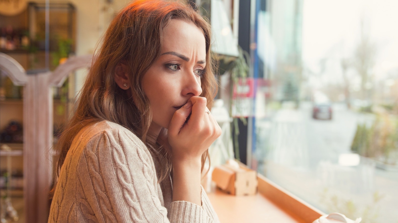 A woman sits looking nervous and unsure of herself to represent limiting beliefs.