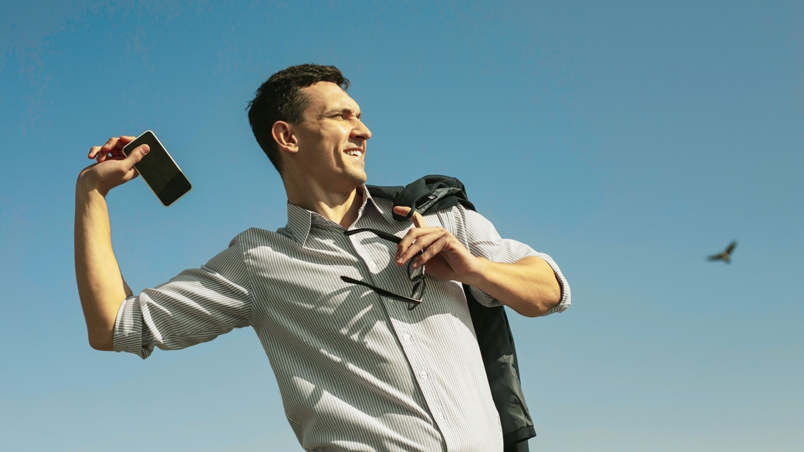 A man happily throws his phone far away after quitting his job.