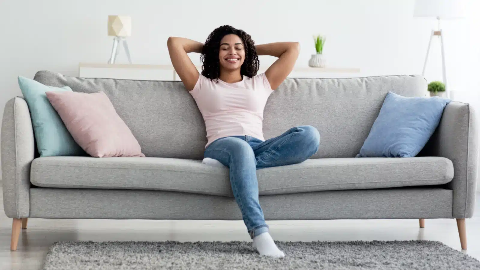 A woman leans back relaxing on the couch, satisfied with her clean house.