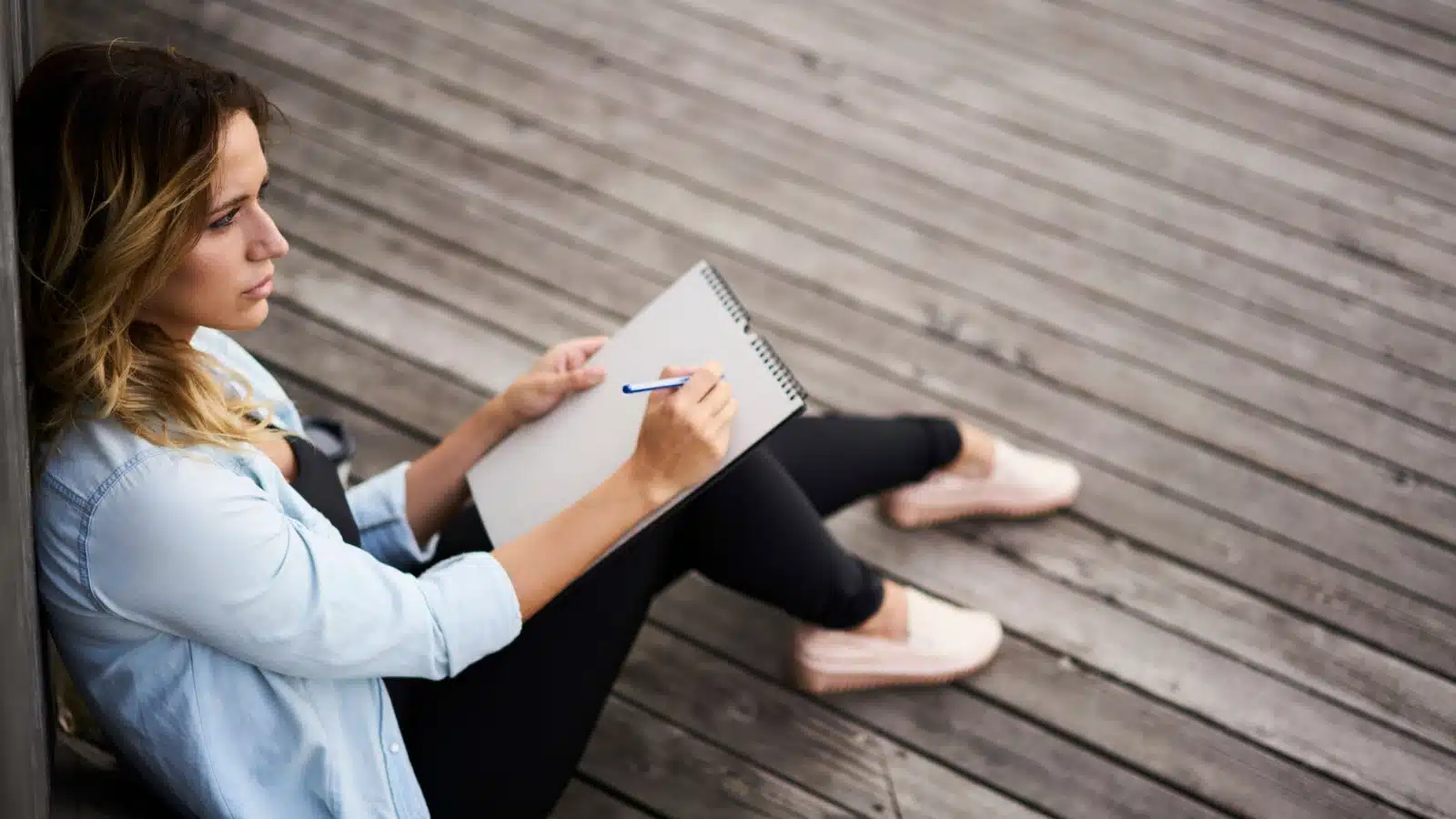 A woman sits with a blank sketchbook unsure of what to draw.