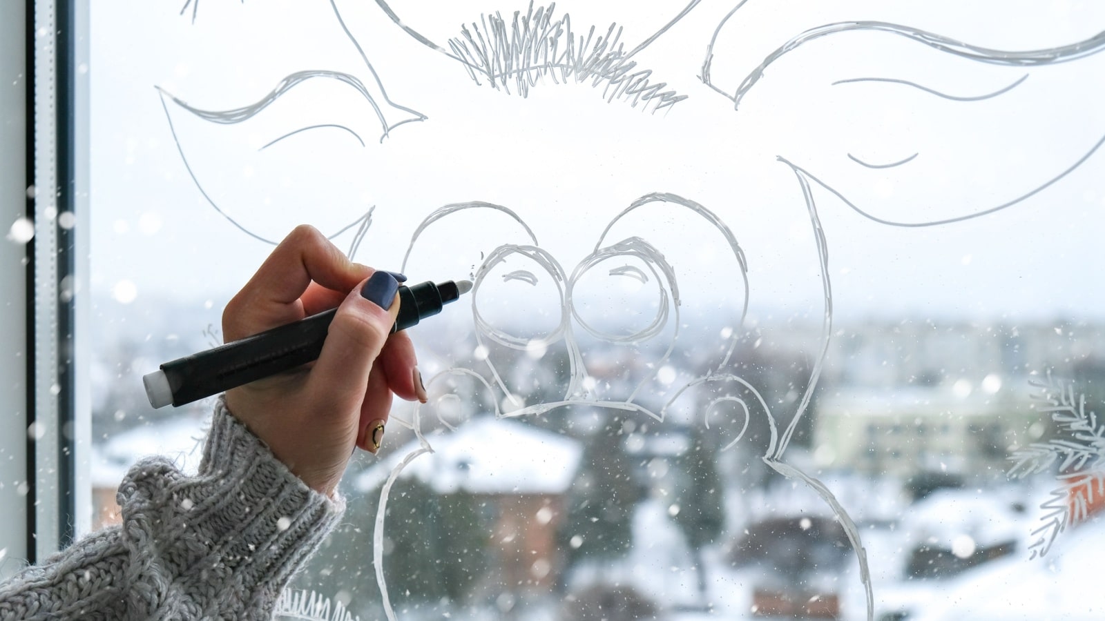 A woman drawing decorations on a window. 