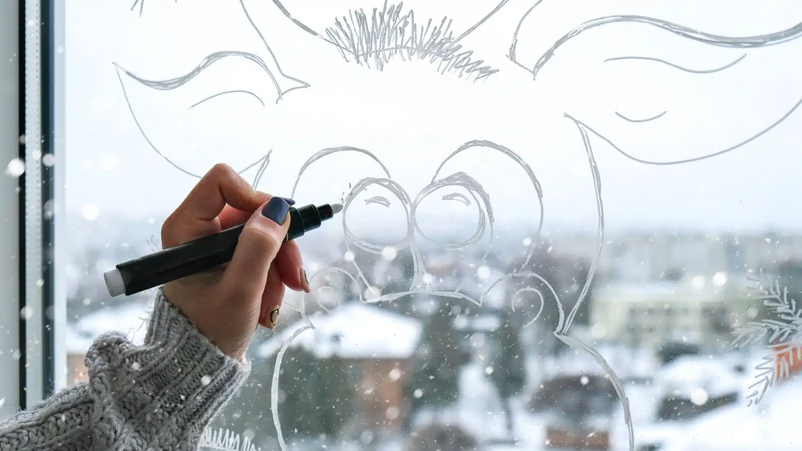 A woman drawing decorations on a window.