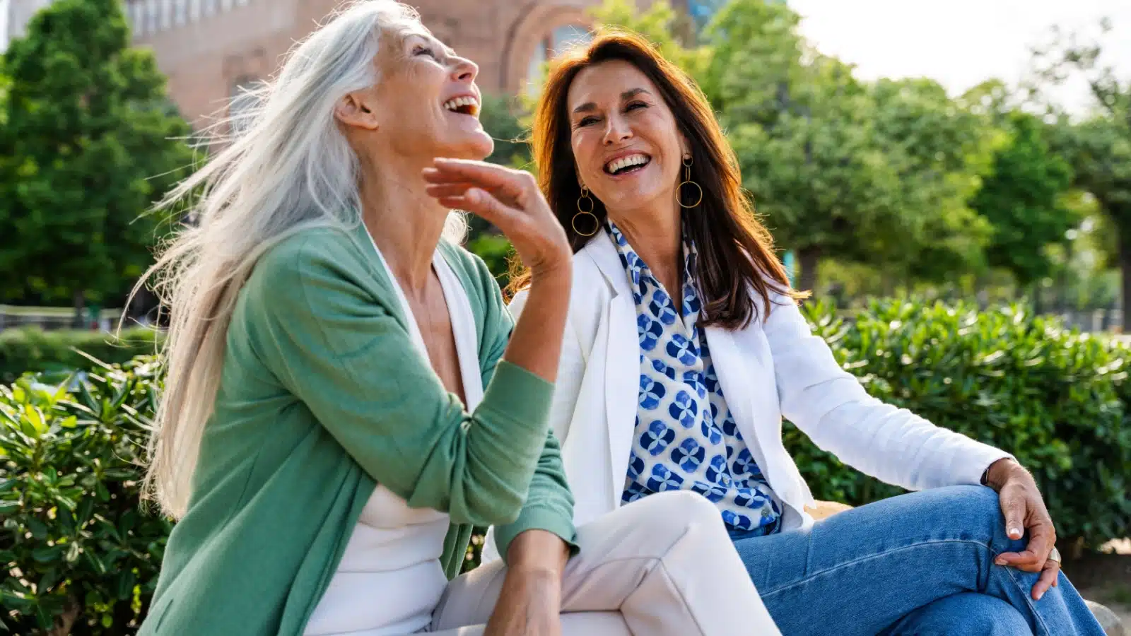 Two older happy single childfree women enjoy a chat outside.