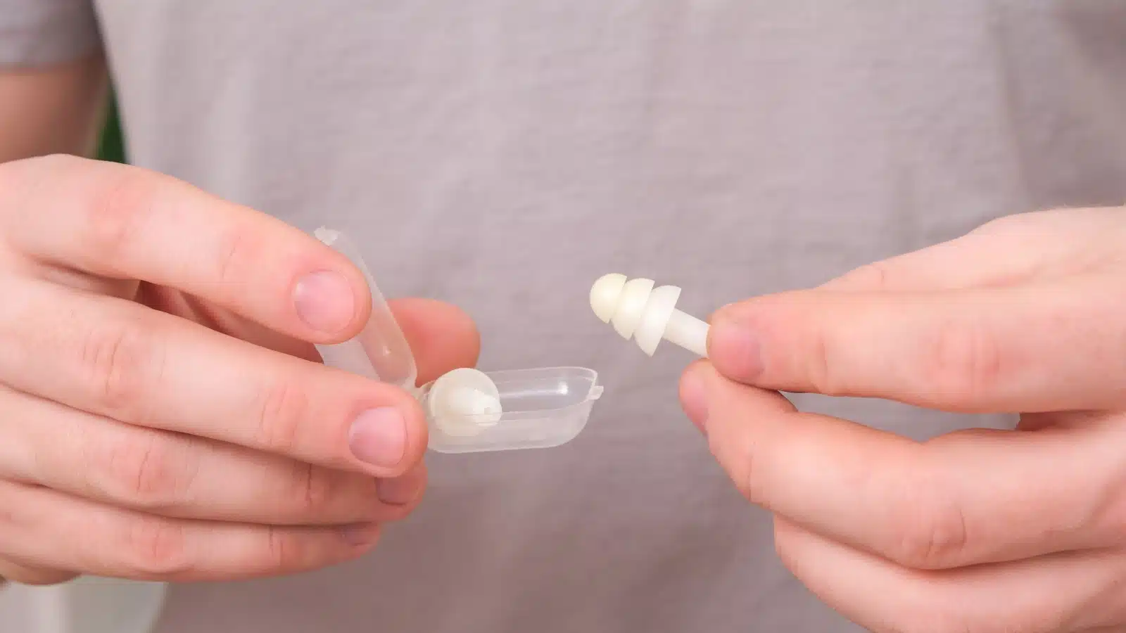 A man opens a case of ear plugs.