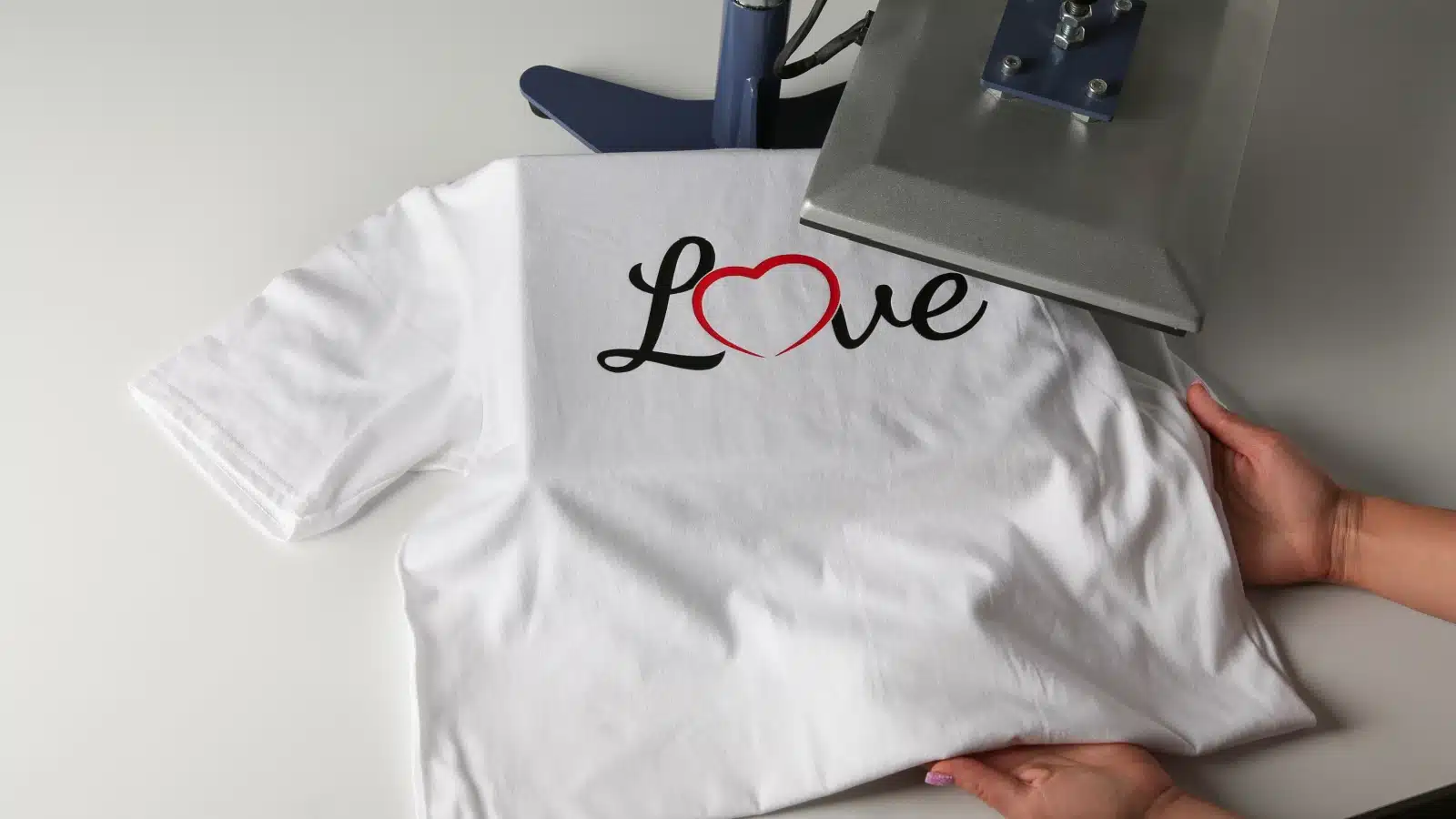 A woman uses a heat press to print a logo on a t-shirt.