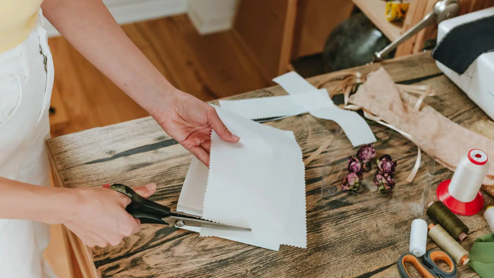A woman uses scissors to cut decorative craft paper.