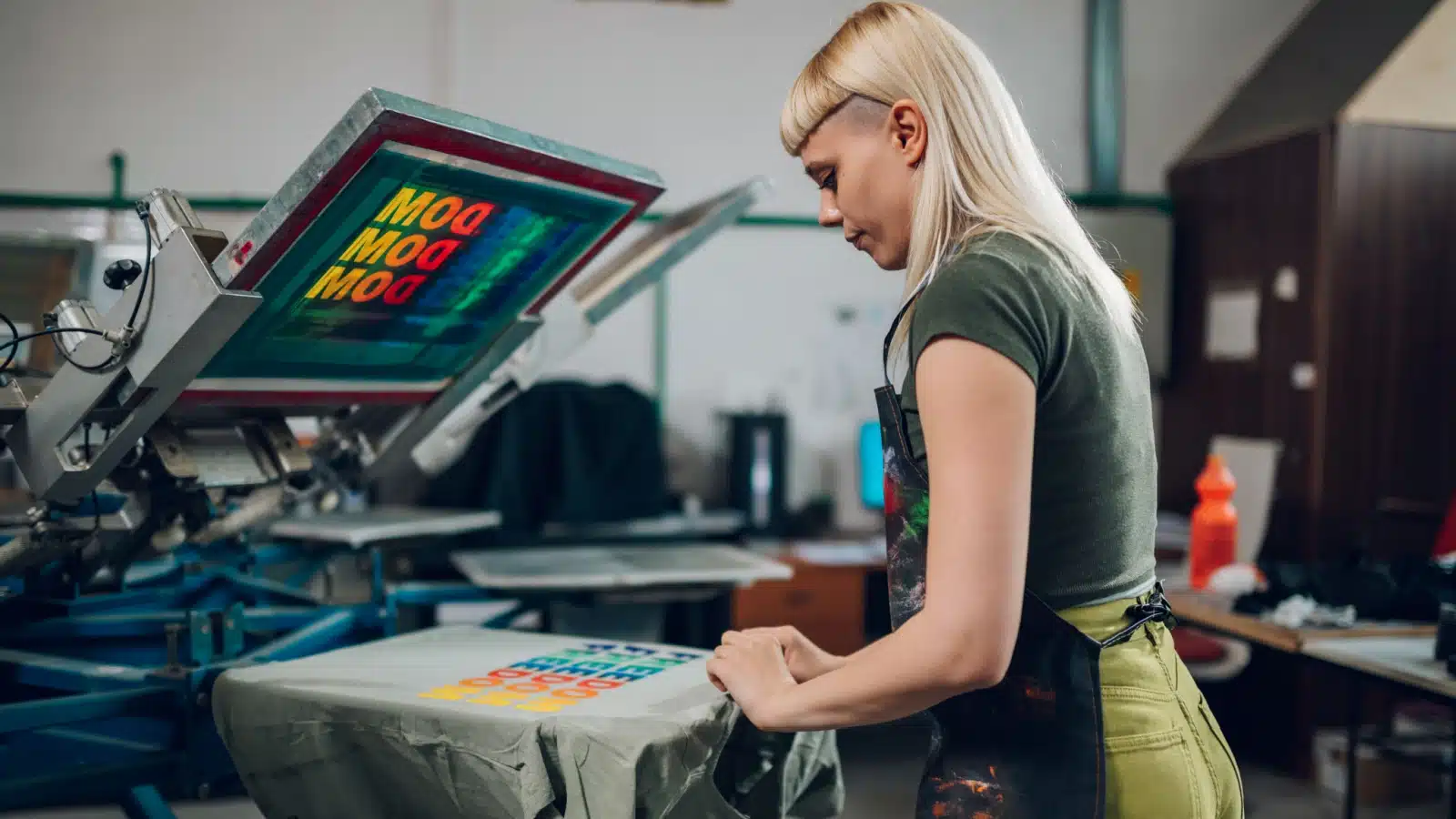 A woman silkscreen printing t-shirts.