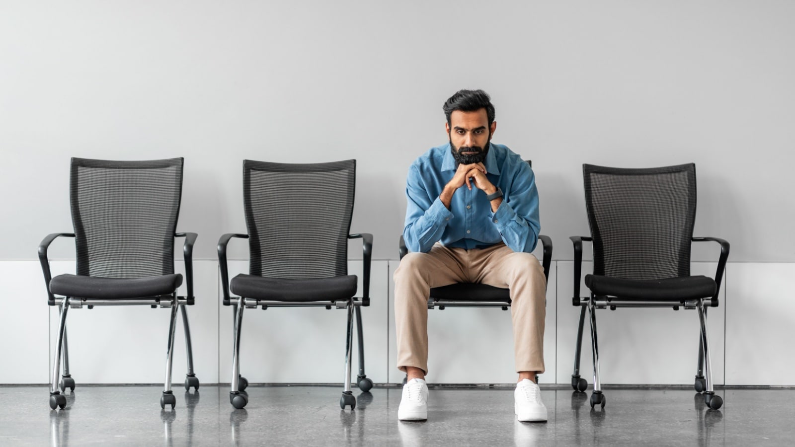 A man sits alone in an hall, to represent waiting for someday.