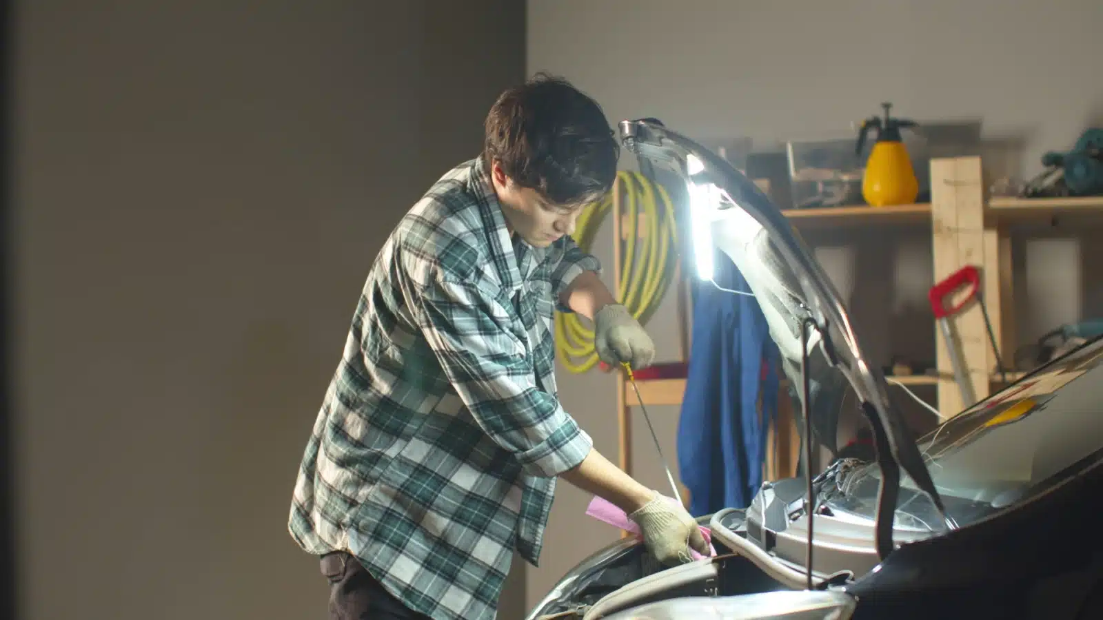 A young man changes the oil in his car.
