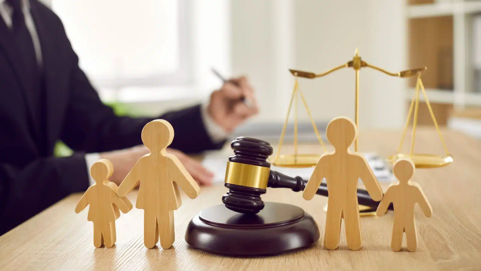 Wooden blocks representing parents and children in front of a judge's gavel to represent child support and custody arrangements.