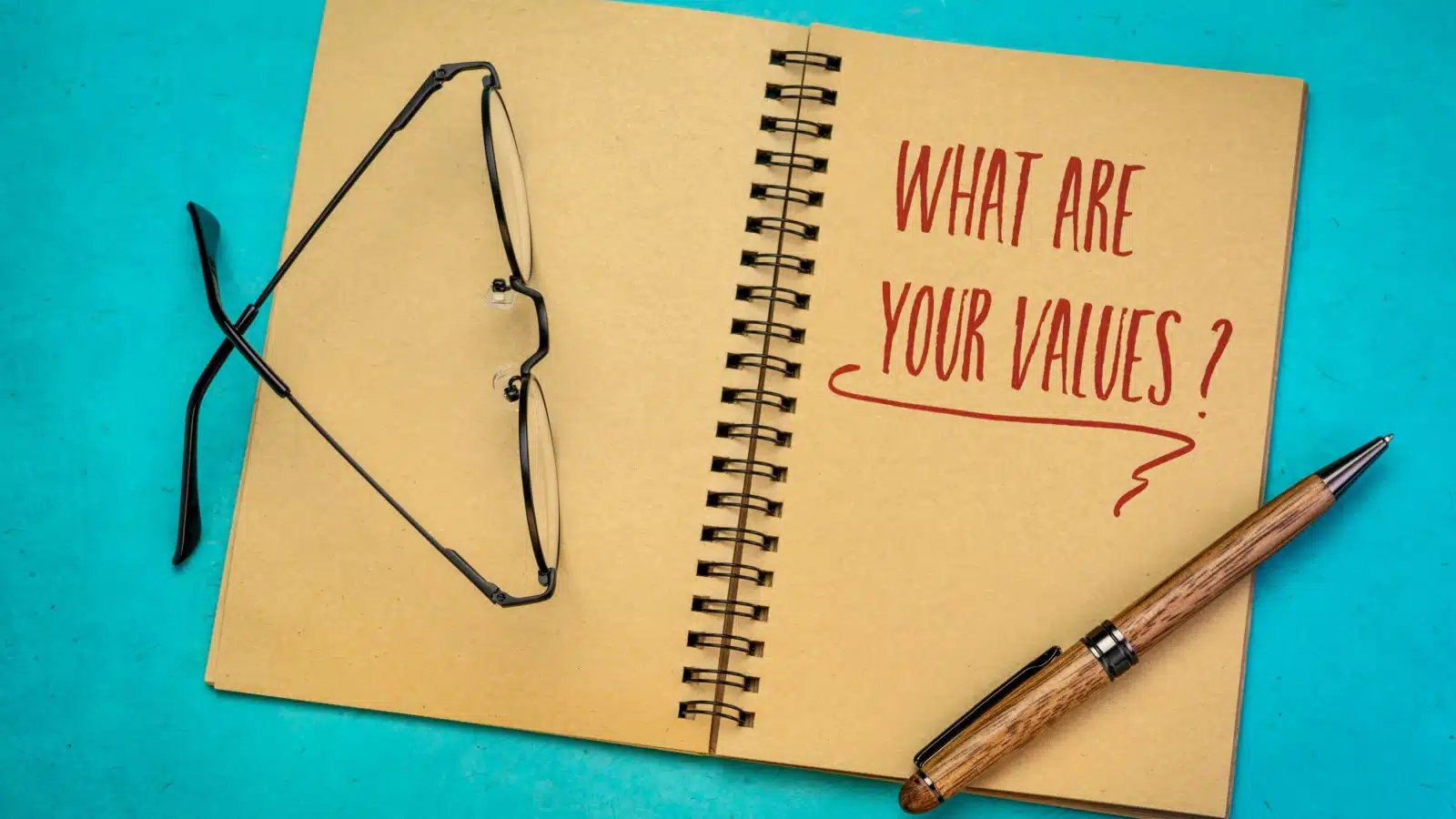 A notebook open with the question "what are your values" written on the page to represent core values.