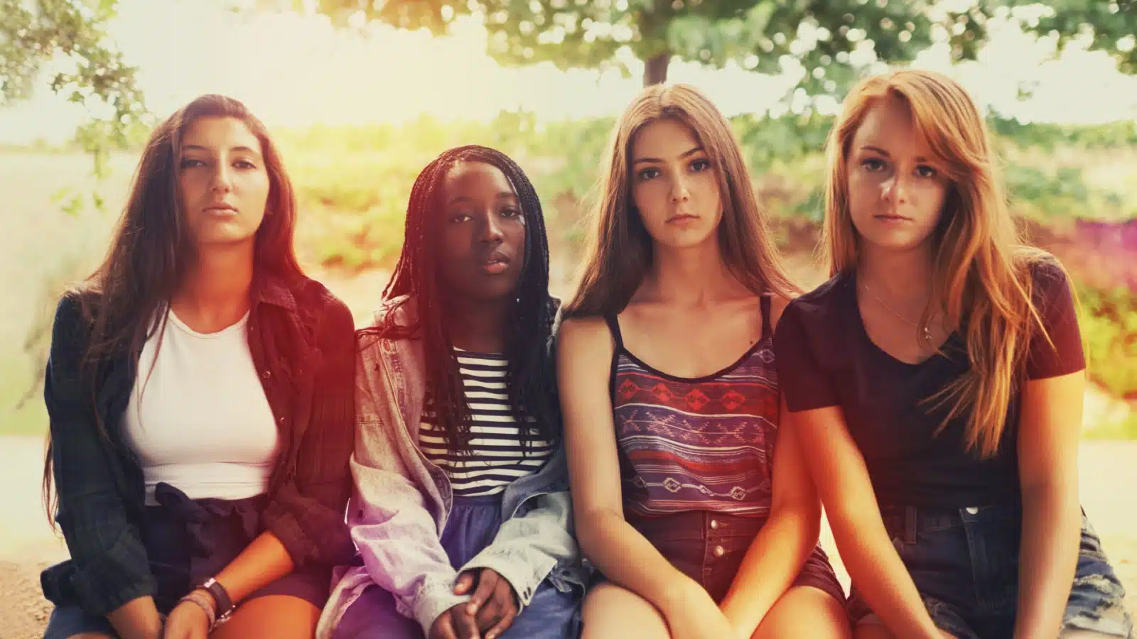 Four displeased looking young women staring into the camera as if someone told a terrible joke that didn't land.