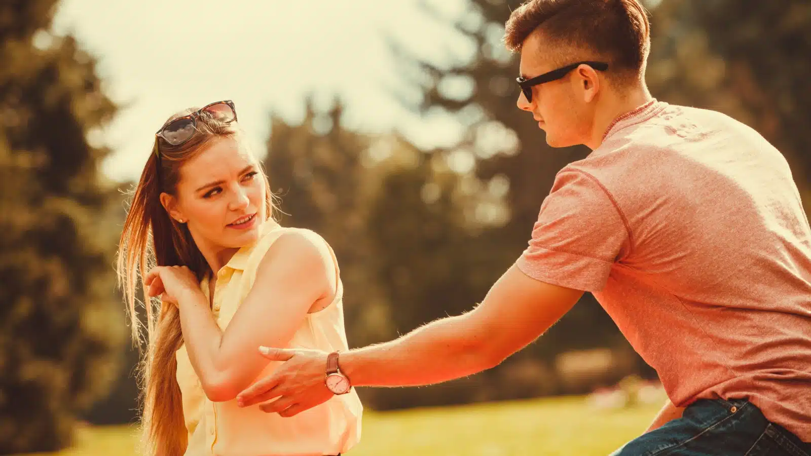 An entitled man attempts to grab a woman's arm to get her attention after she has rejected him.