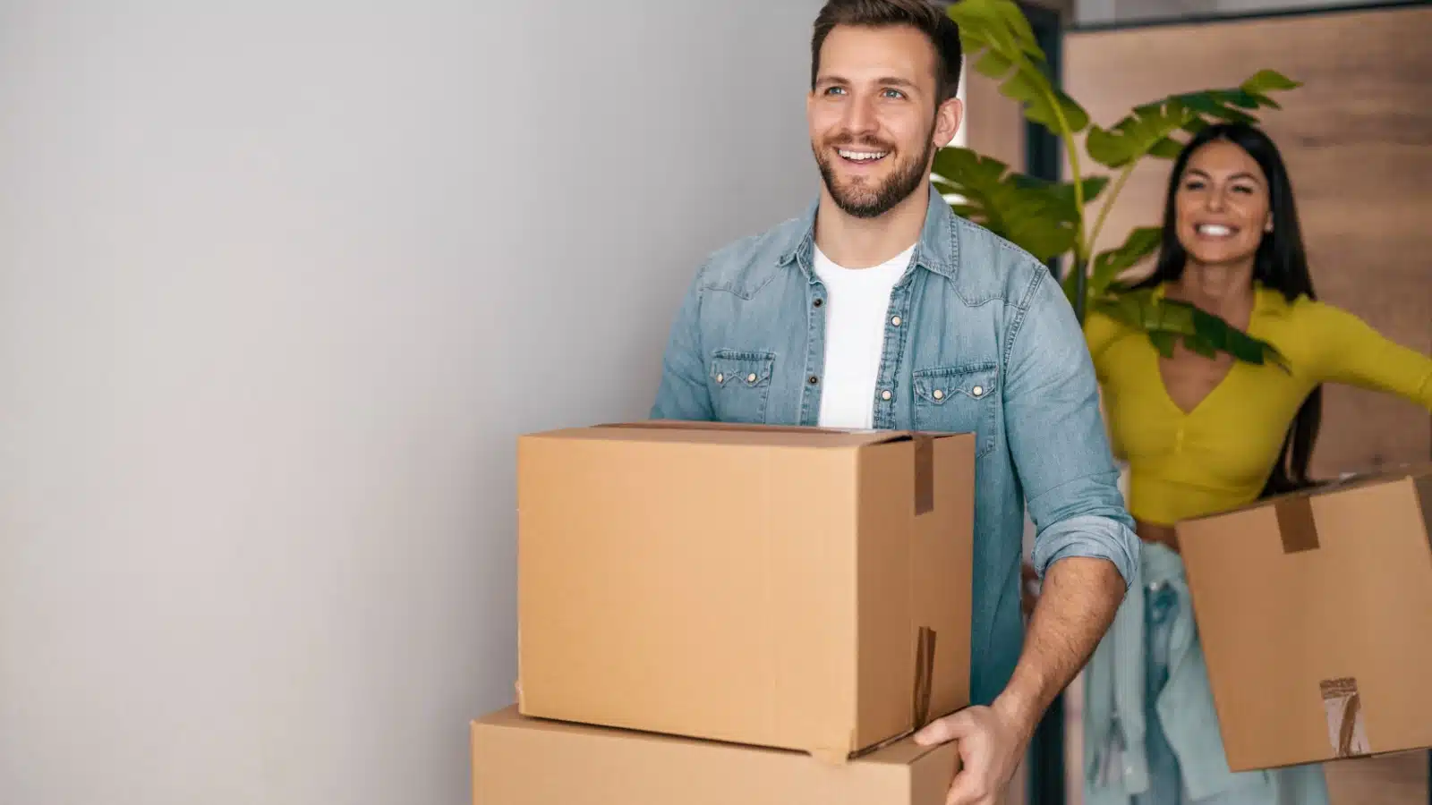 A happy couple carries moving boxes into their new home.