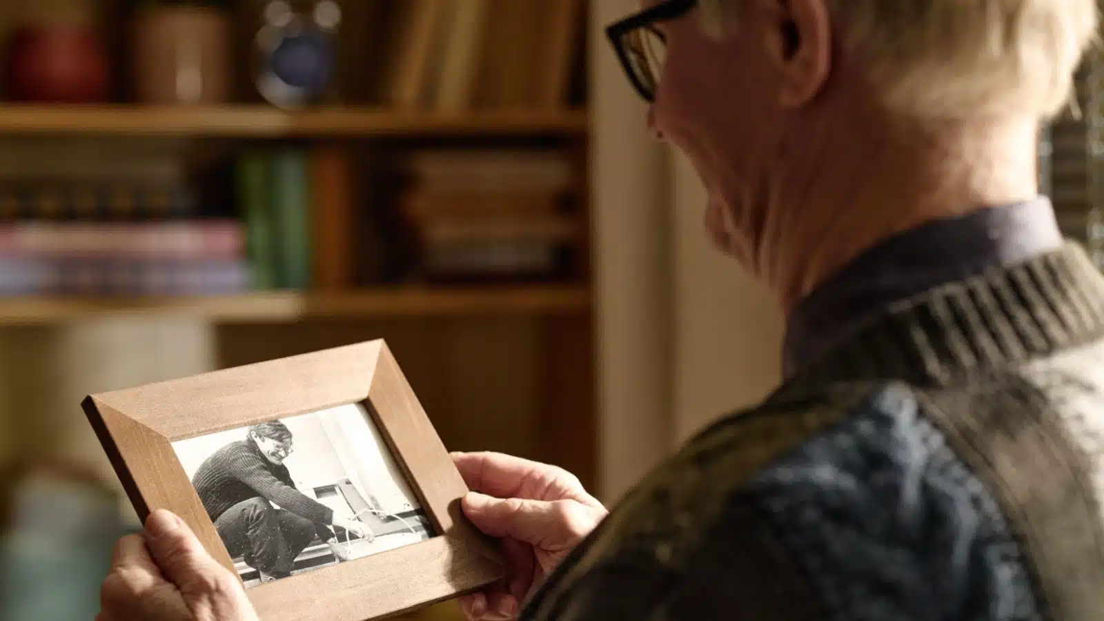 An senior looks fondly on an old photograph of himself to represent reflecting on the past.