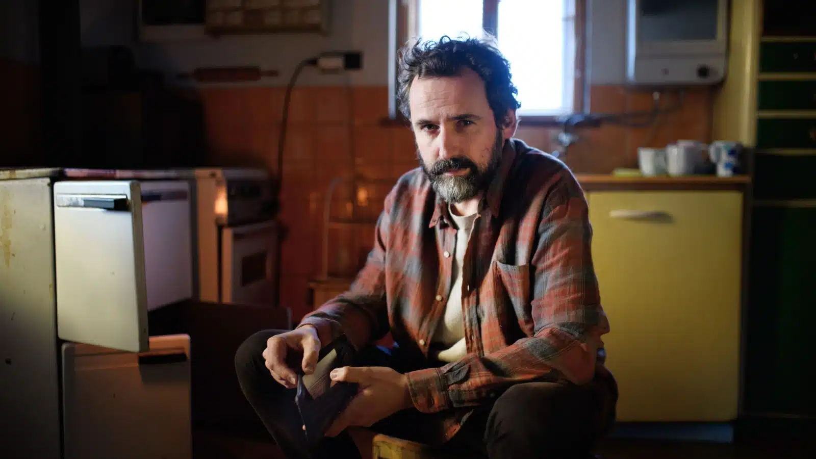 Portrait of a man with no money sitting in his kitchen to represent the realities of being poor.