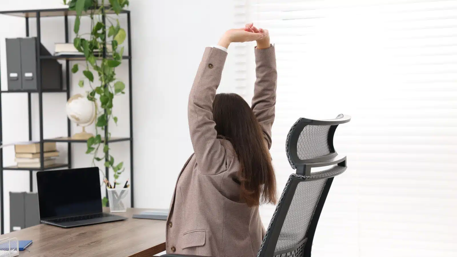 A woman stretches at her desk.