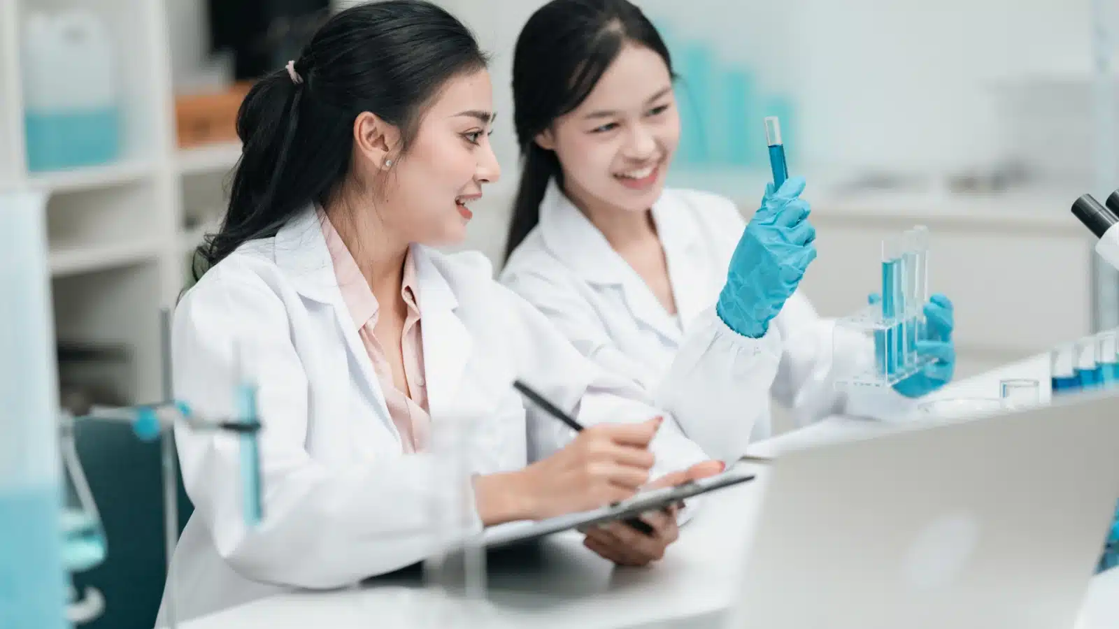 Two researches in a science lab recording results. 