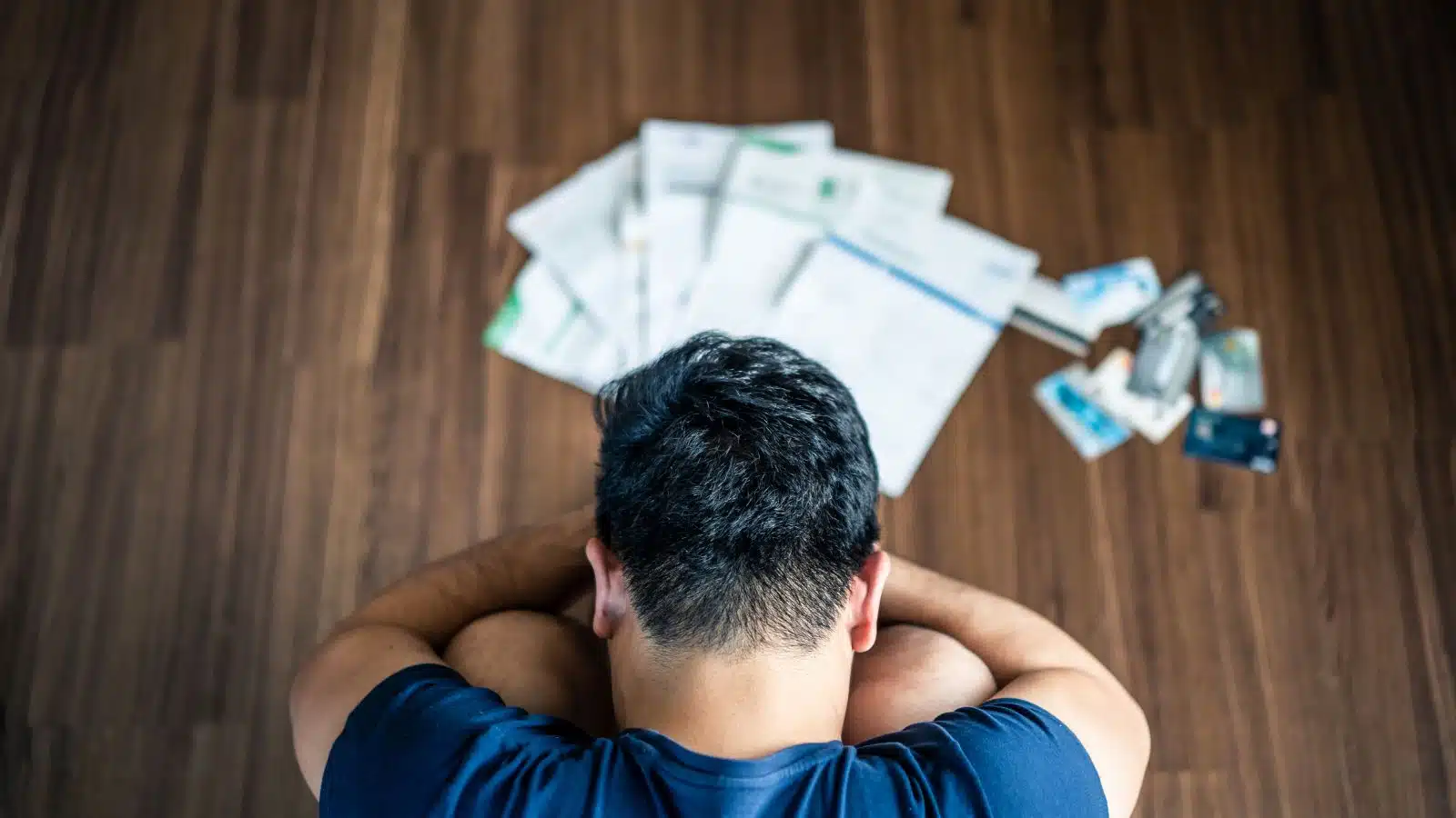 A sad stressed man sits in front of a pile of bills he can't pay, to represent America's real welfare problem. 