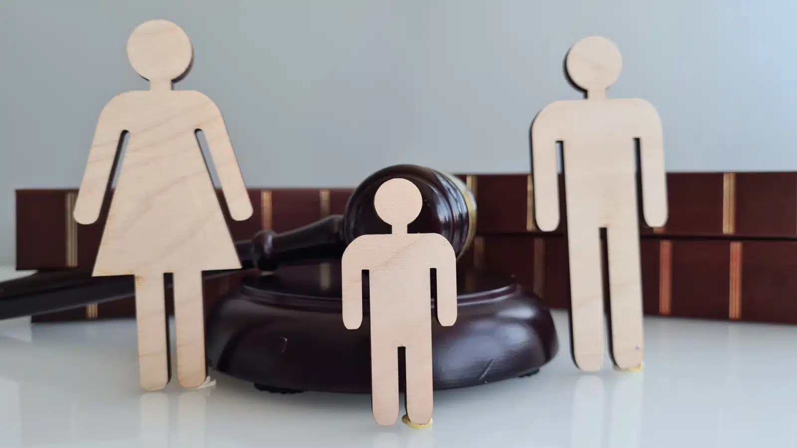 Wooden figures of a mother, father, and child in front of a judge's gavel to represent family law.
