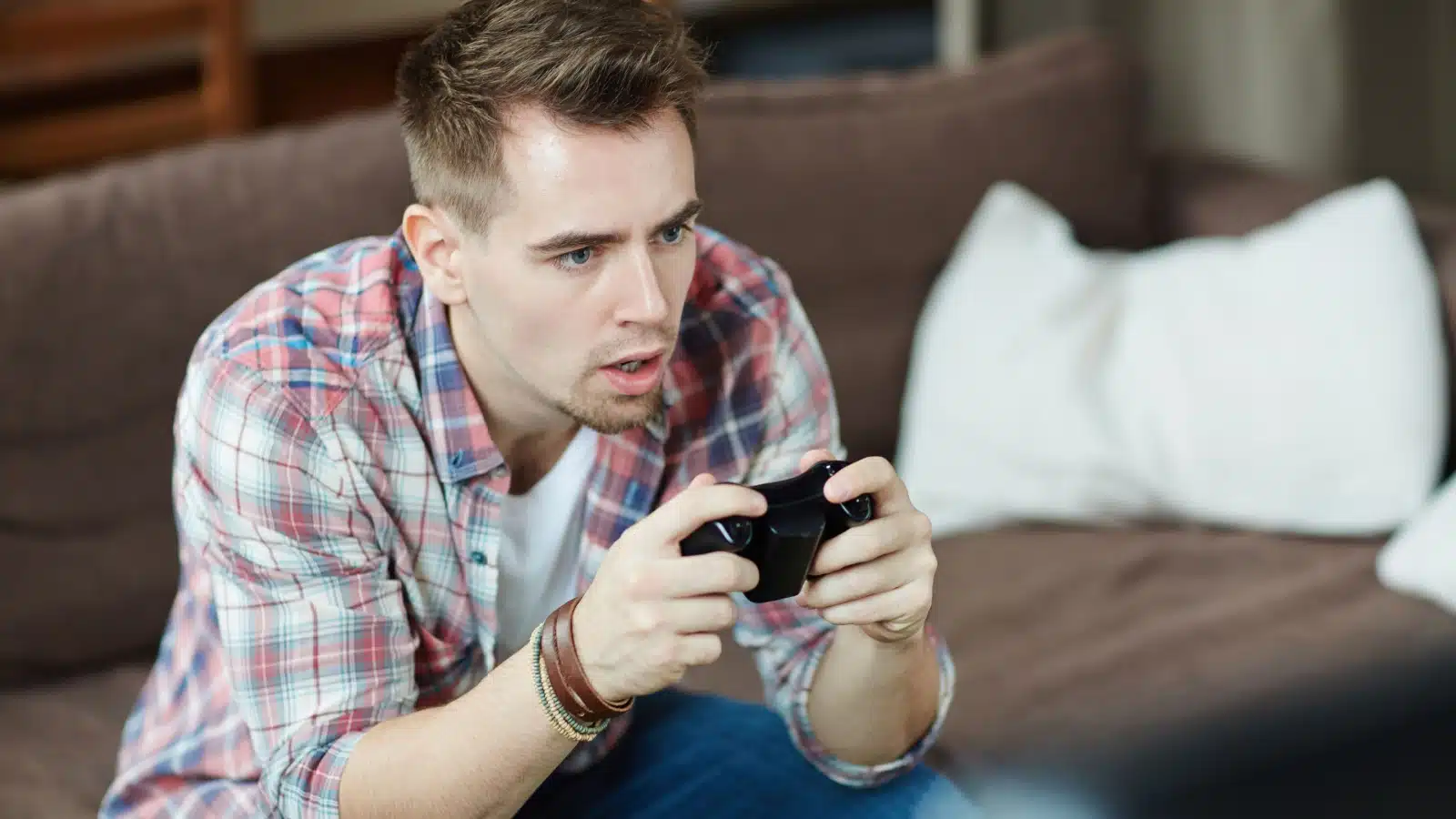 A man focuses on his video game. He looks like he'd be oblivious to anything else around him. The image represents the question "Do video games rot minds?"