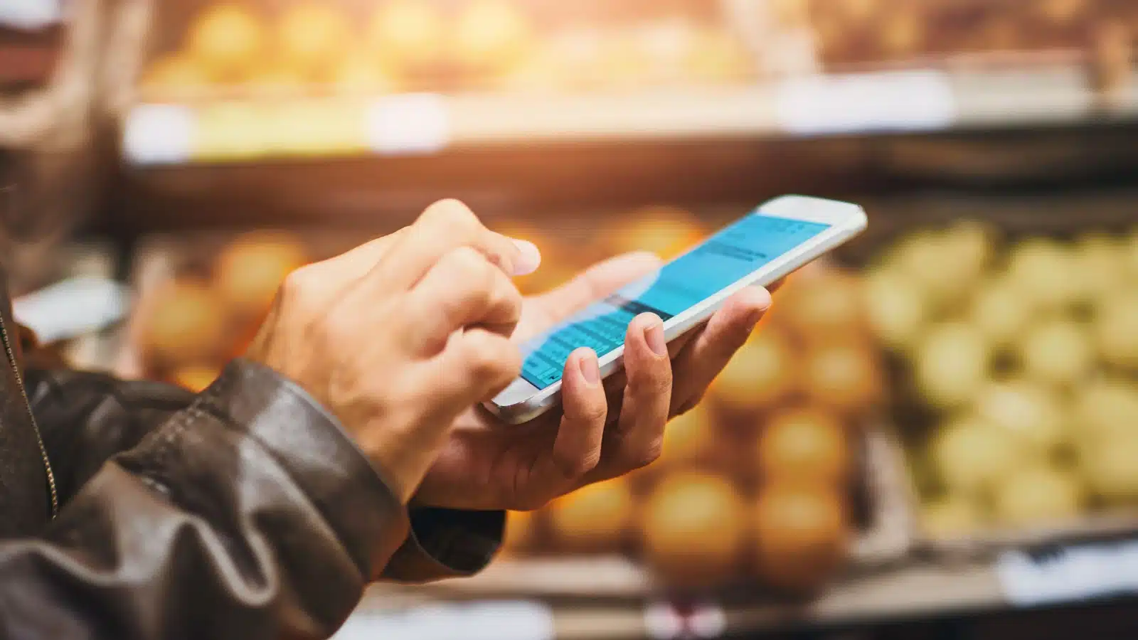 A man uses his cell phone in a grocery store.