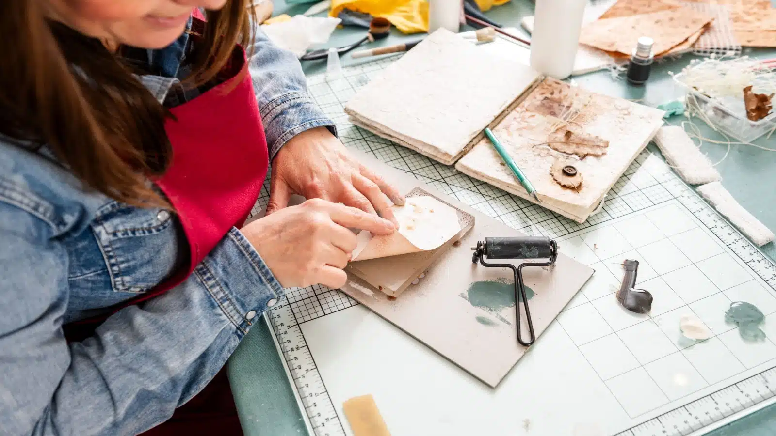 A woman uses a variety of interesting materials while making her scrapbook.