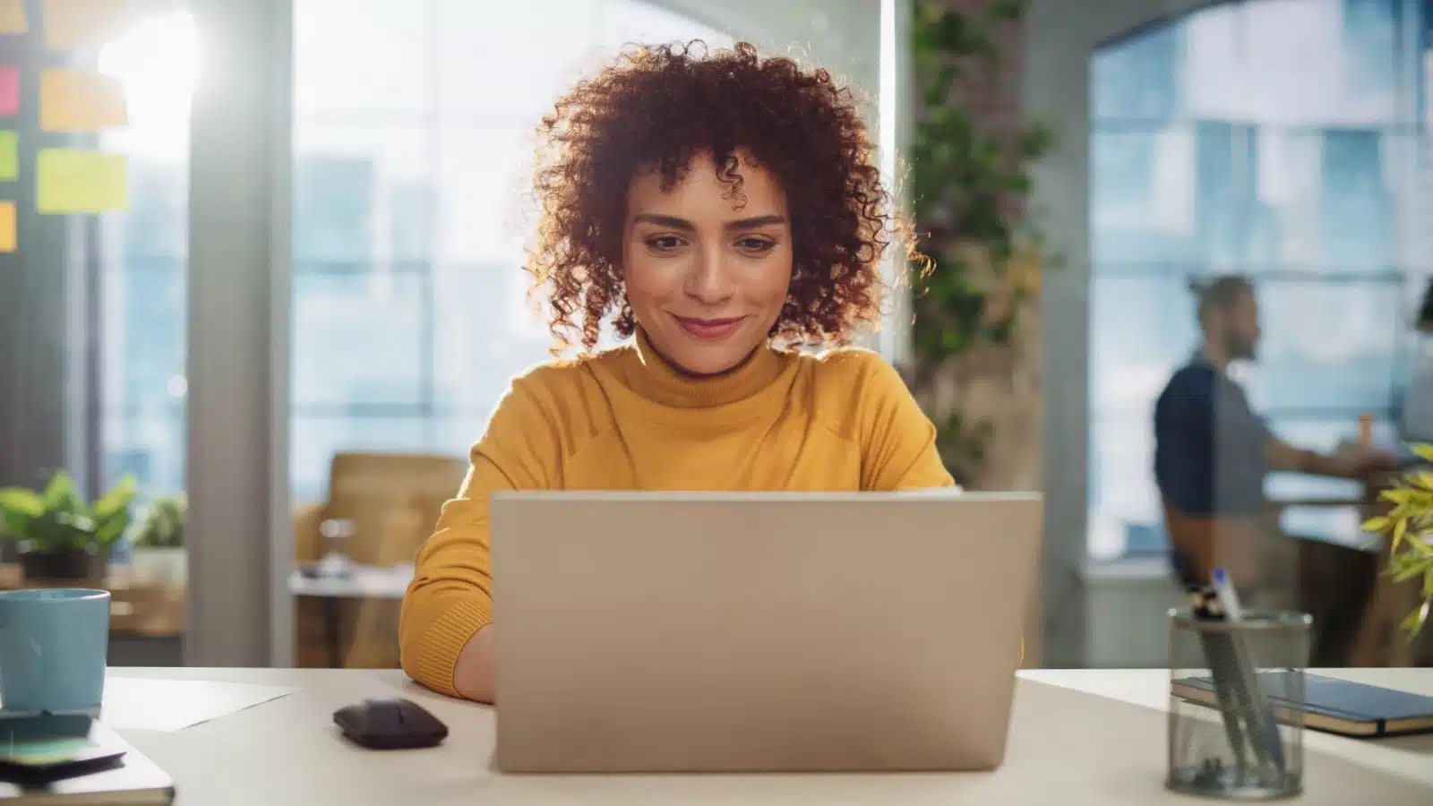 A woman working on her laptop with a knowing smile, as if she just solved a complicated problem. 