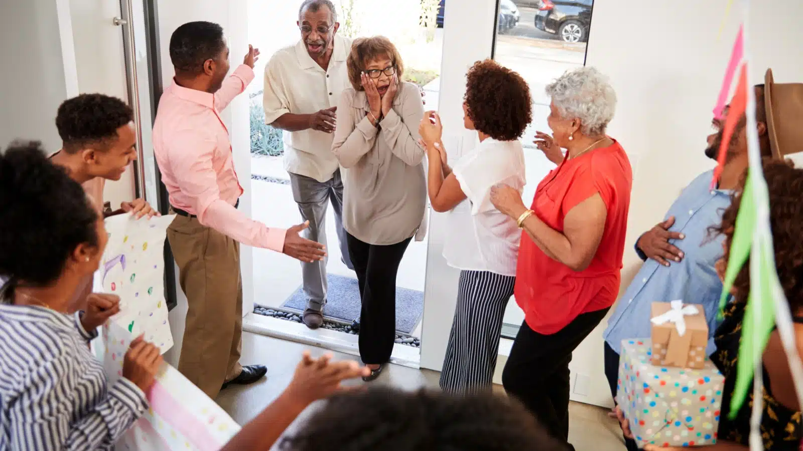 A family throws a surprise party for an older relative, who genuinely looks surprised.