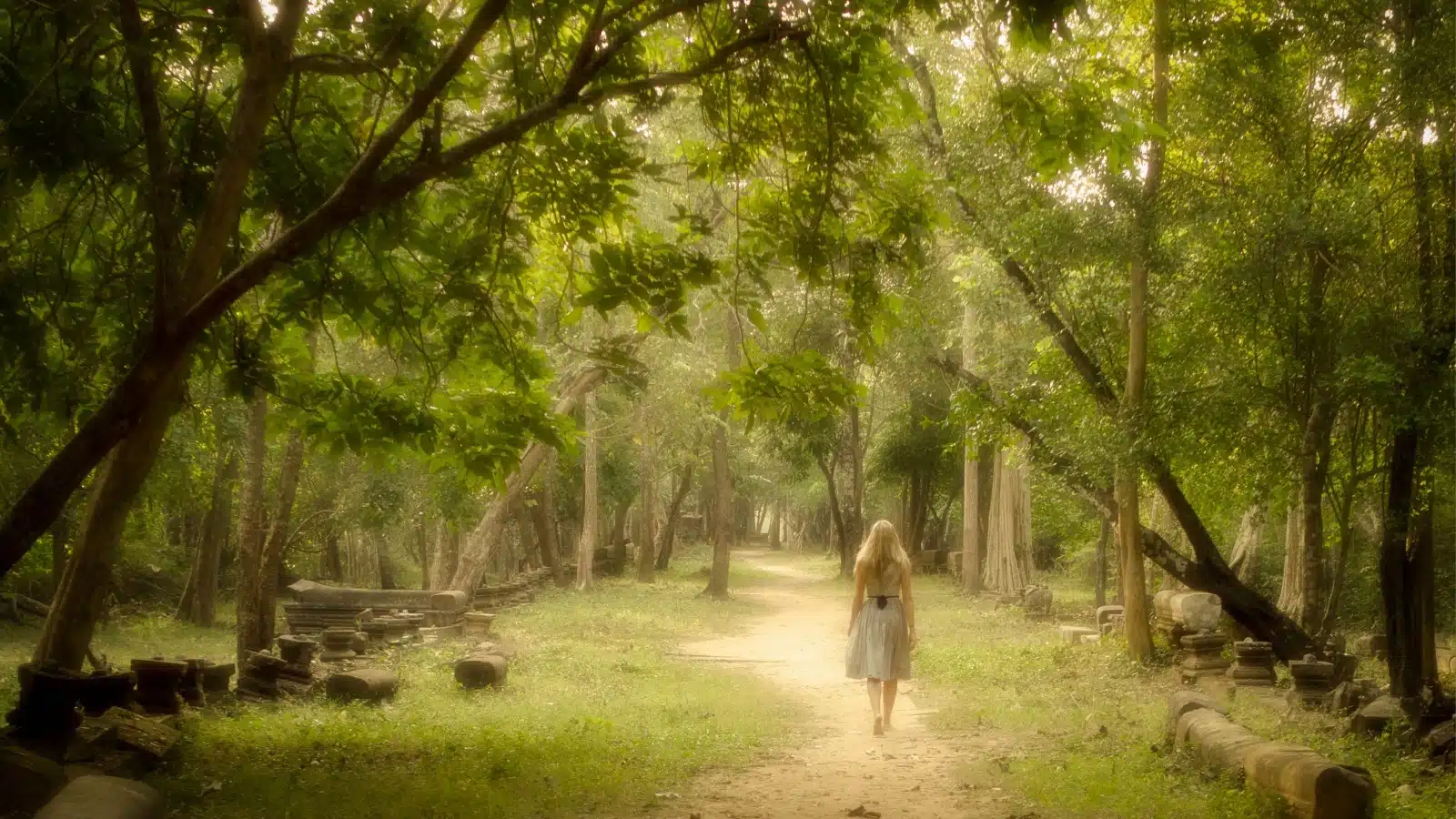 A woman walking through a mystical looking forest to represent the road less traveled. 