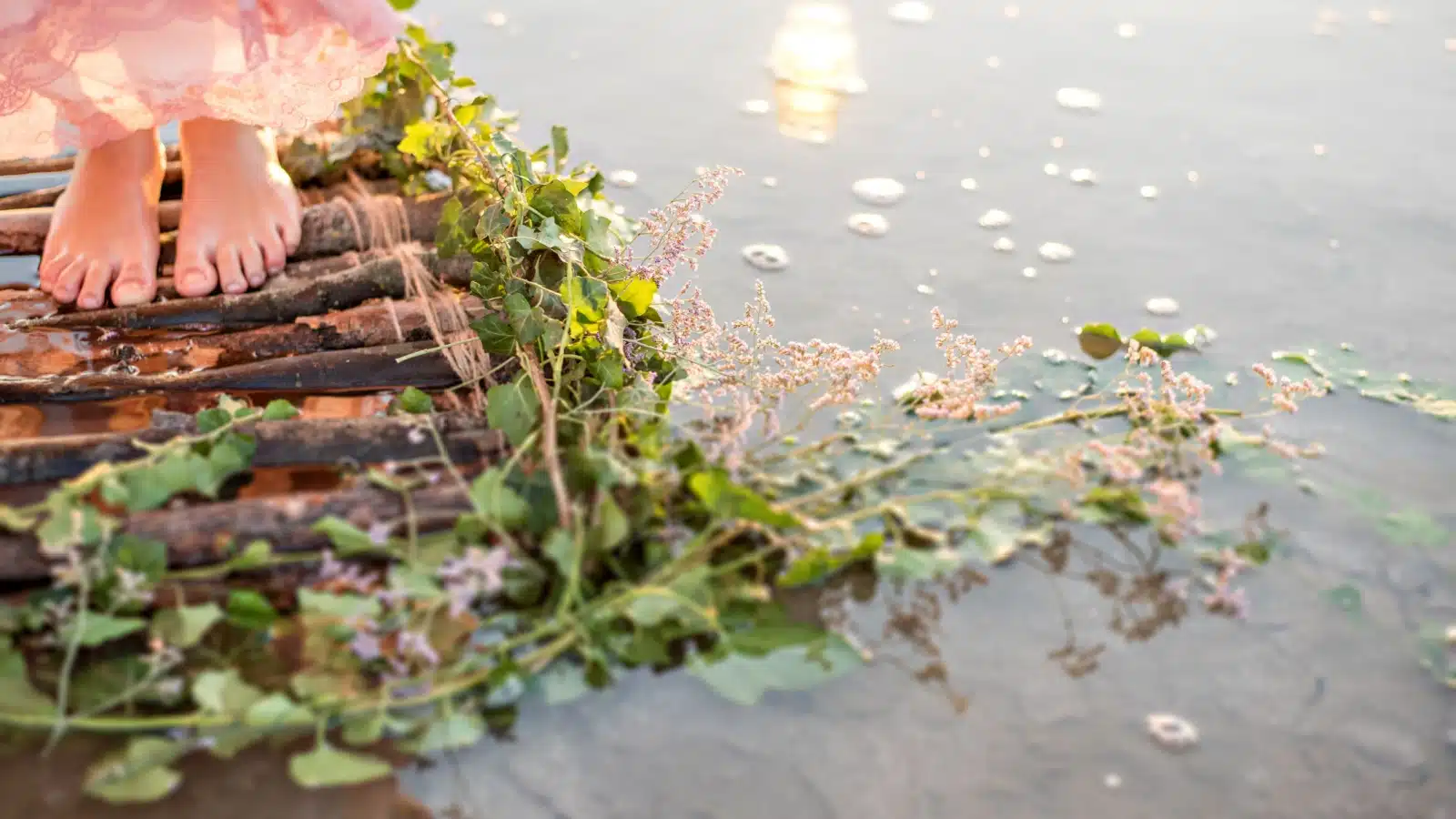 A girl's feet standing on a wooden raft in desolate waters. 