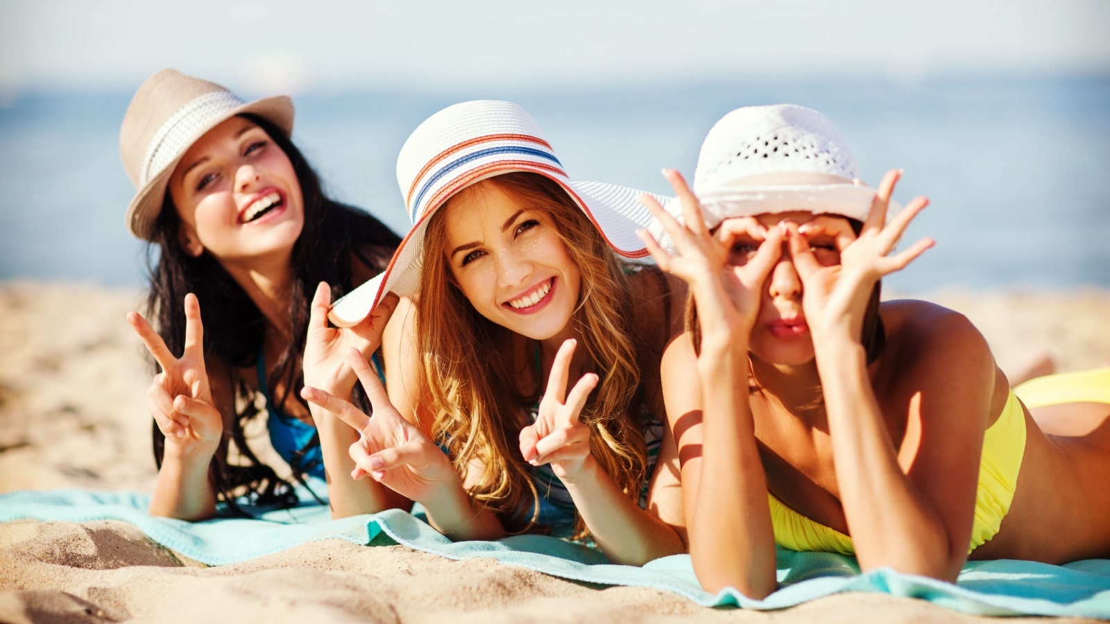 Three happy friends laying on the beach to represent the best summer quotes.