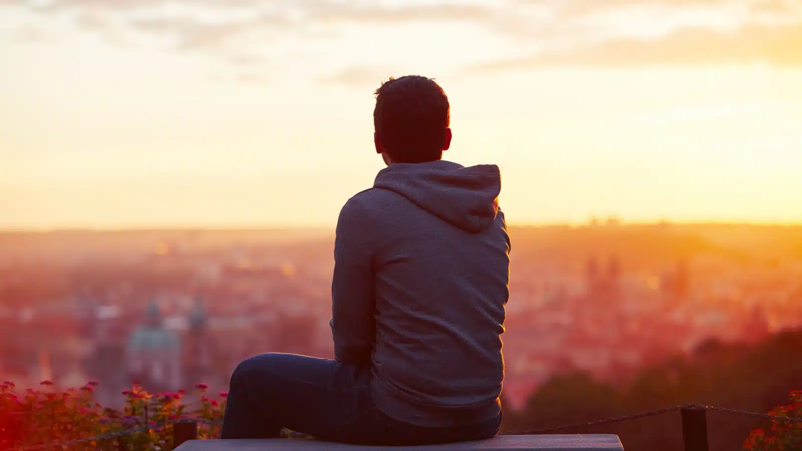 A young man watching sadly as sun sets on summer. 