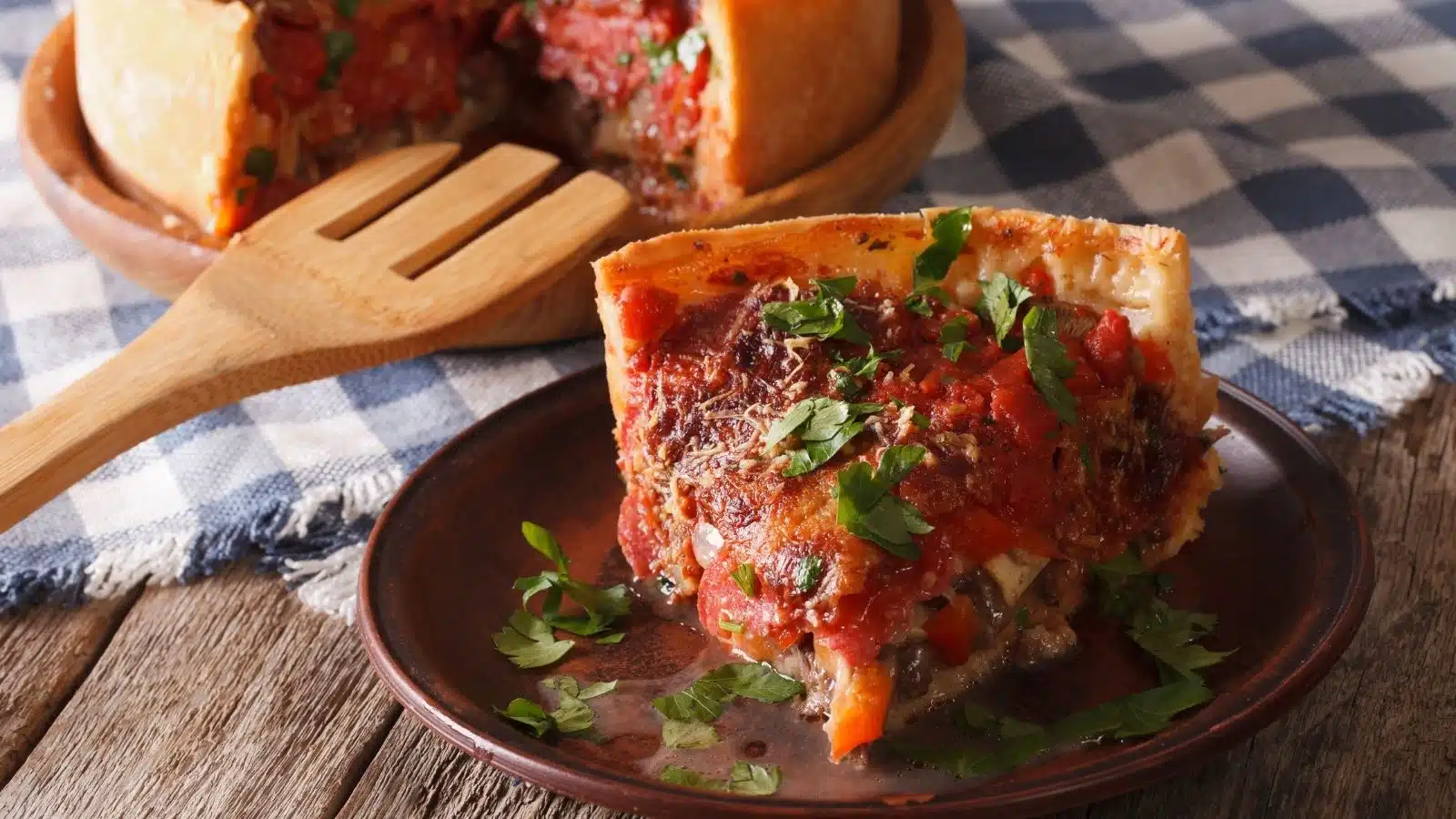 A slice of Chicago style deep-dish pizza on a plate.