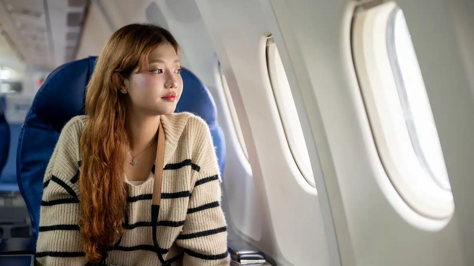 A relaxed woman looks out the window on an airplane.