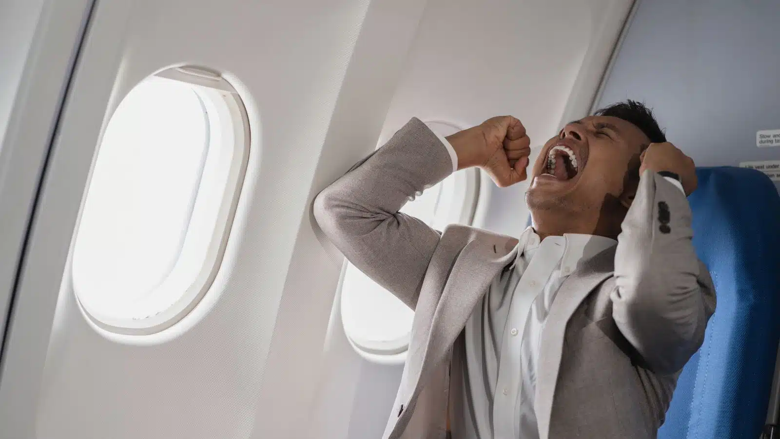 A stressed man yells on an airplane.
