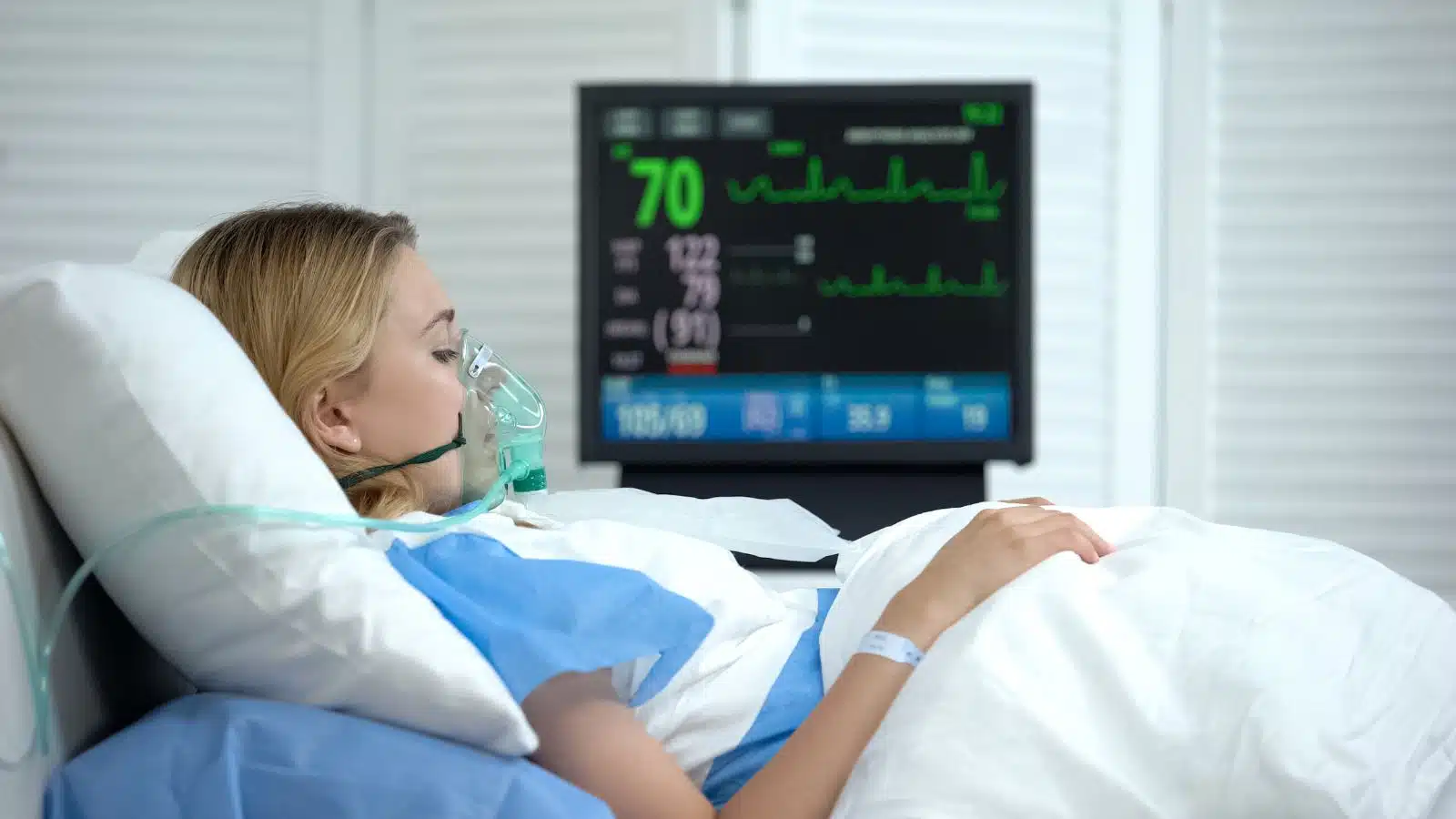 A pregnant woman lies in a hospital bed with a ventilator after experiencing pregnancy complications. 