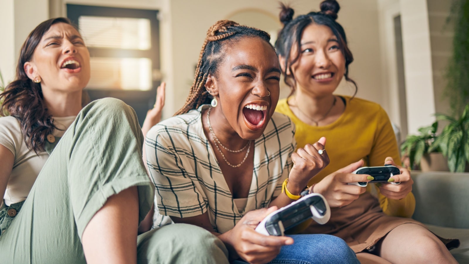 Three female friends playing a video game together to represent women in gaming statistics.