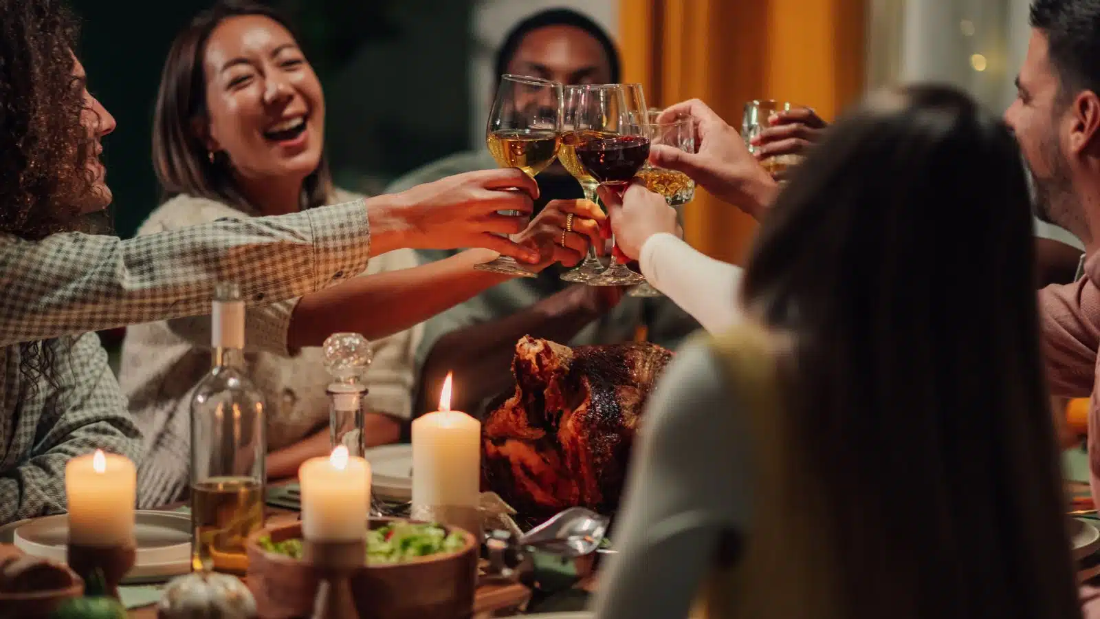 Friends toasting around the Thanksgiving dinner table during a friendsgiving.