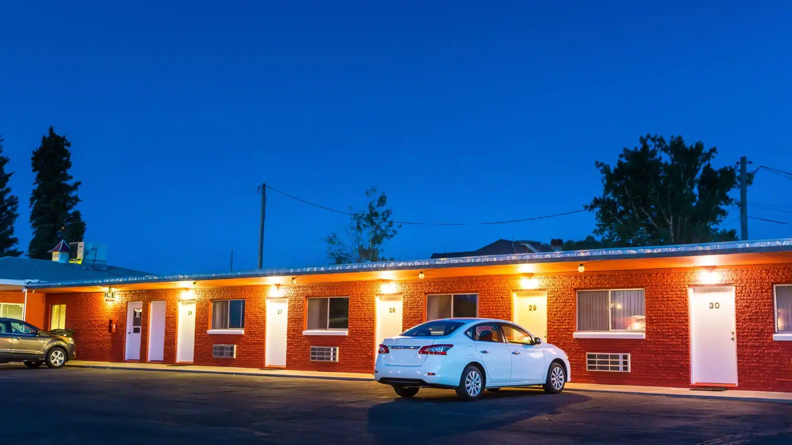 A roadside motel at dusk with a single car in the lot.