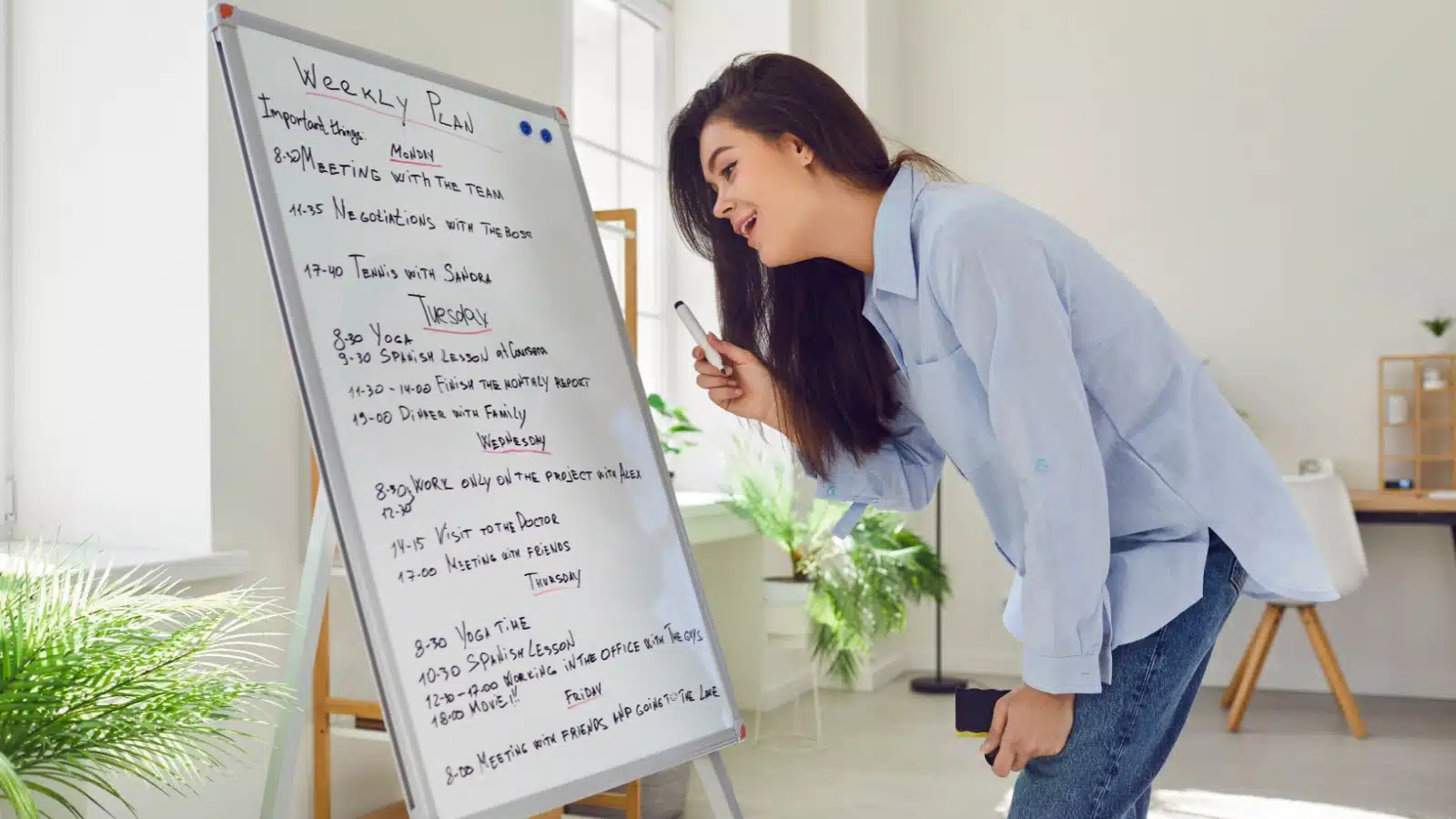 A woman looking at her weekly task list on a whiteboard.
