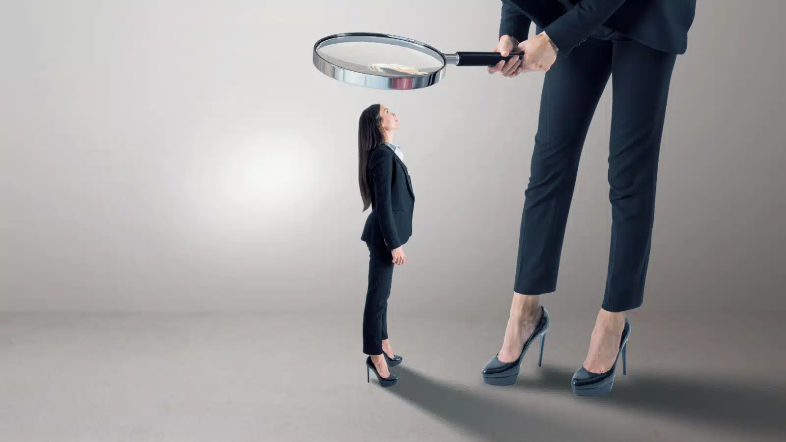 A woman examines a tiny version of herself with a magnifying glass.