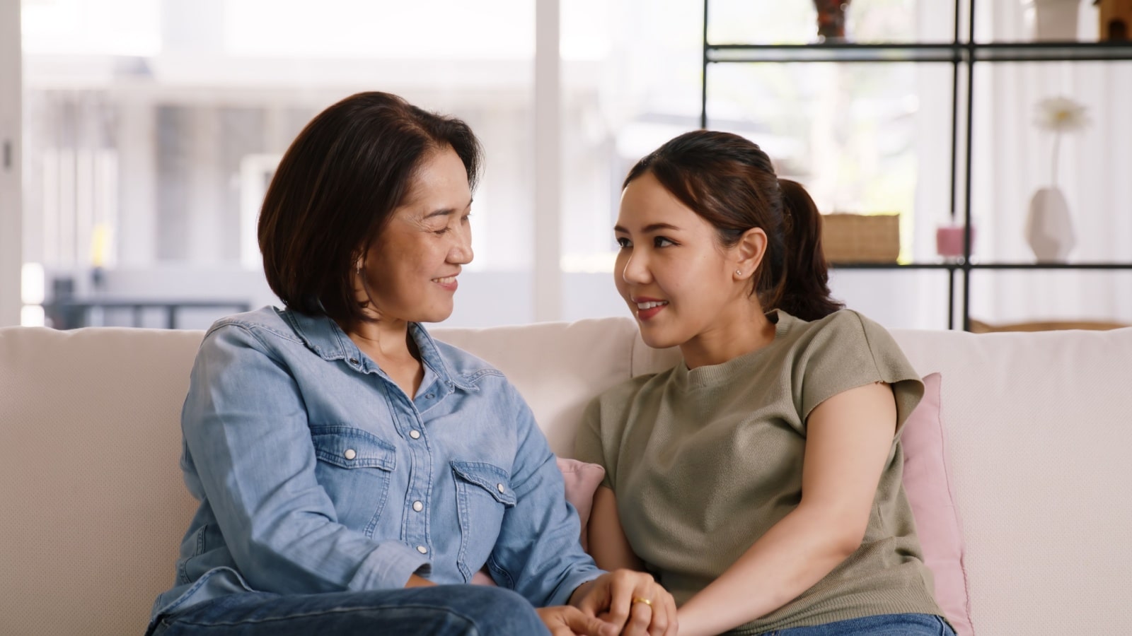 A mother and daughter sit on the couch, talking about their feelings, to represent emotional labor.