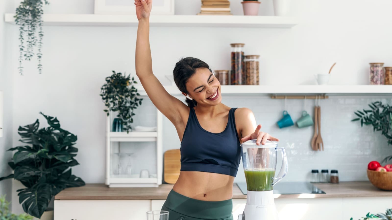 A woman joyfully prepares a healthy morning smoothie.